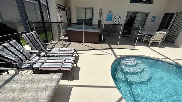 A poolside area with lounge chairs, a hot tub, and a ceiling fan. - 4BD/3B,EXECUTIVE VILLA WITH SPA,MUST SEE,10 MIN FROM DISNEY (Kissimmee)