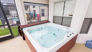 A hot tub in a room with large windows, a view of a swimming pool, and a chair. - 4BD/3B,EXECUTIVE VILLA WITH SPA,MUST SEE,10 MIN FROM DISNEY (Kissimmee)