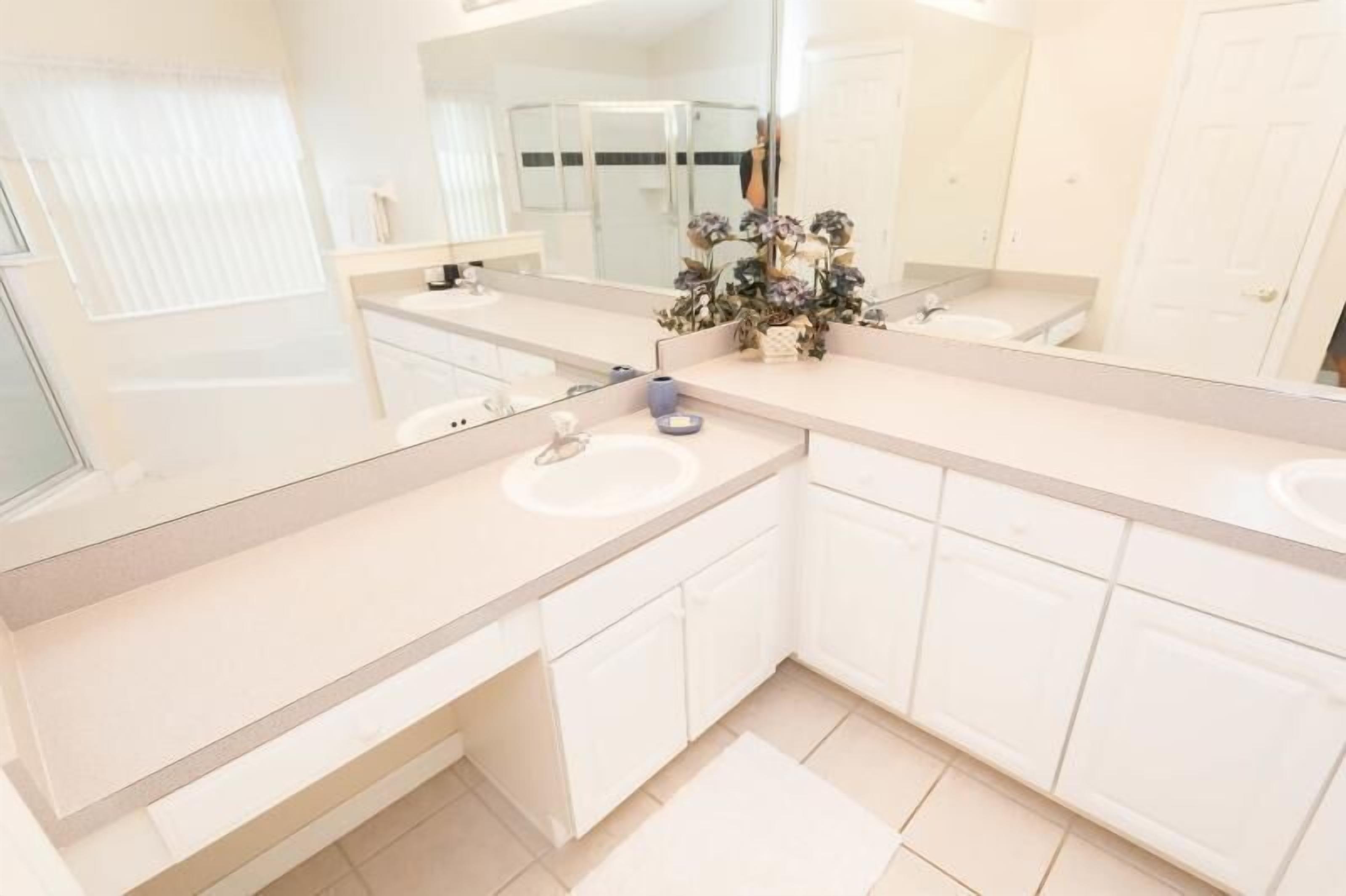 A modern bathroom with two sinks, a large mirror, and a shower area.