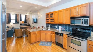 A modern kitchen with wooden cabinets, stainless steel appliances, and a central island. - On Broadway Above Boot Barn (Nashville)