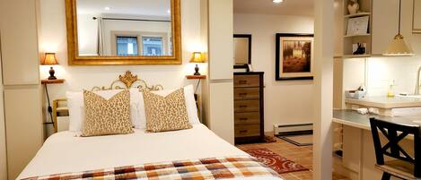 A hotel room with a bed, a desk, a chair, a dresser, and a mirror.