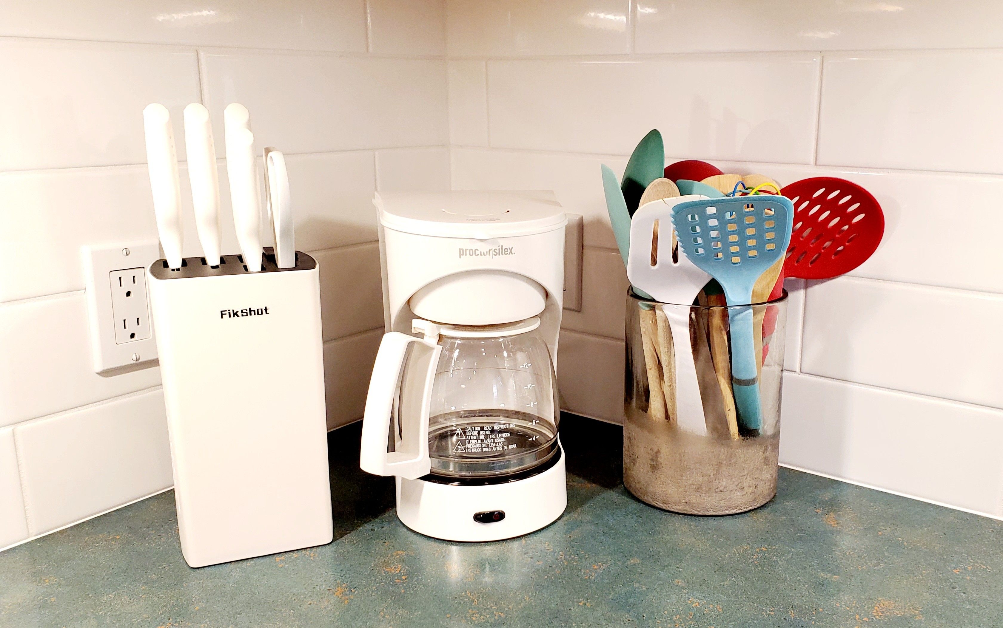 Una cucina con una macchina per il caffè, un portacoltelli e un contenitore per utensili.