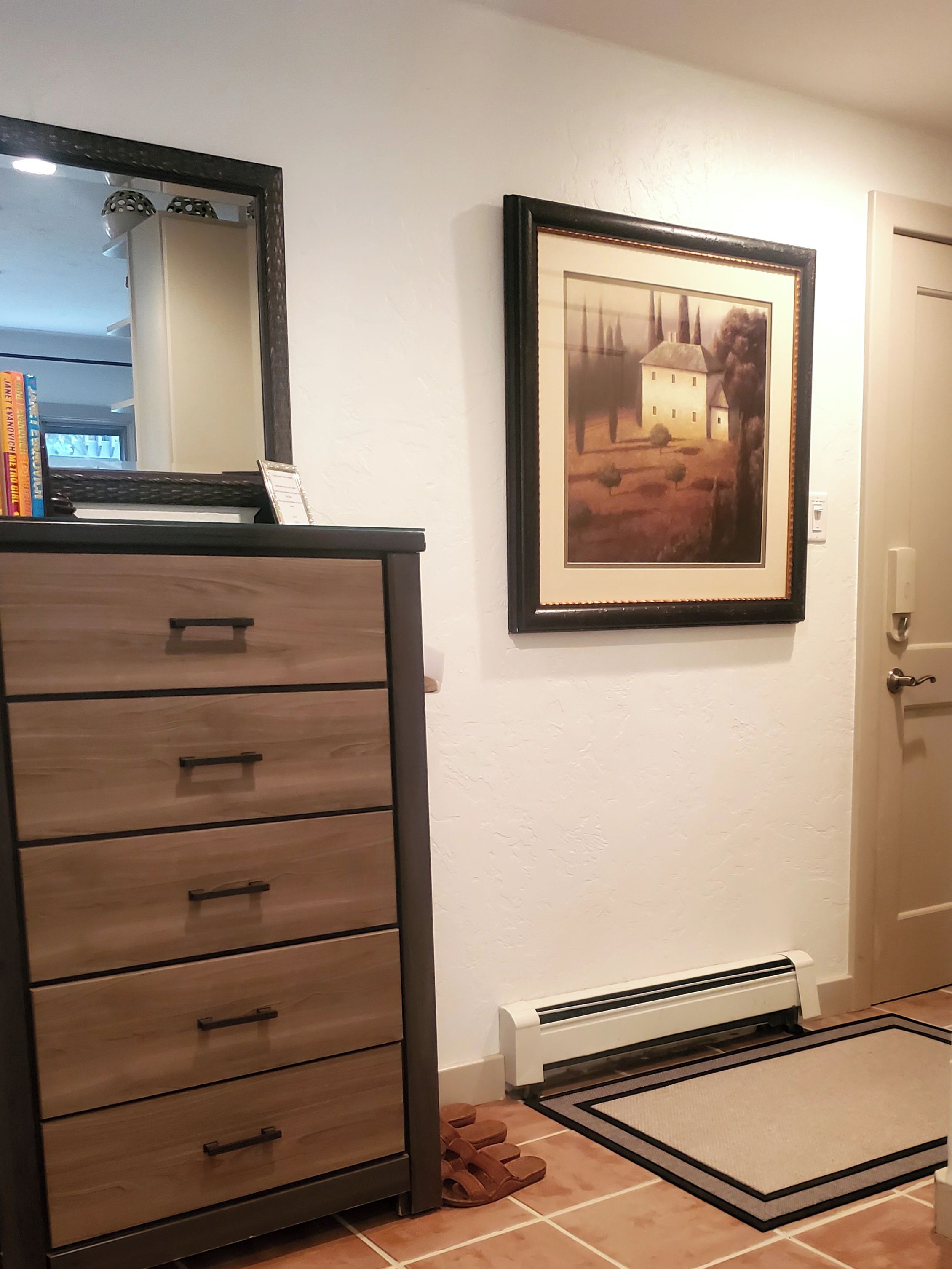 Una habitación con un aparador de madera, un cuadro en la pared y una puerta.