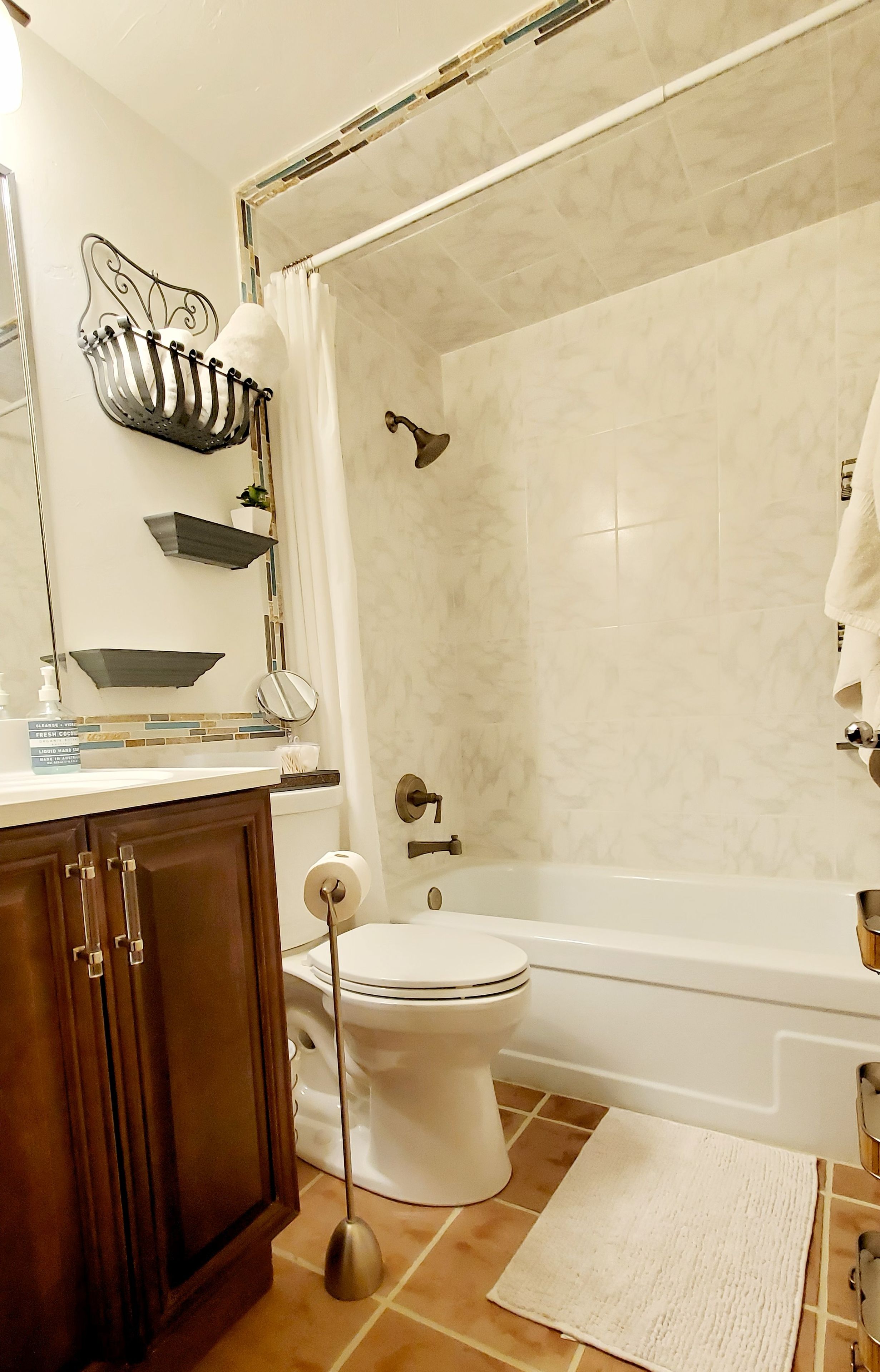 A bathroom with a toilet, bathtub, shower, and a towel rack.
