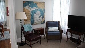 Una sala de estar con un mapa grande en la pared, un televisor y dos sillones.