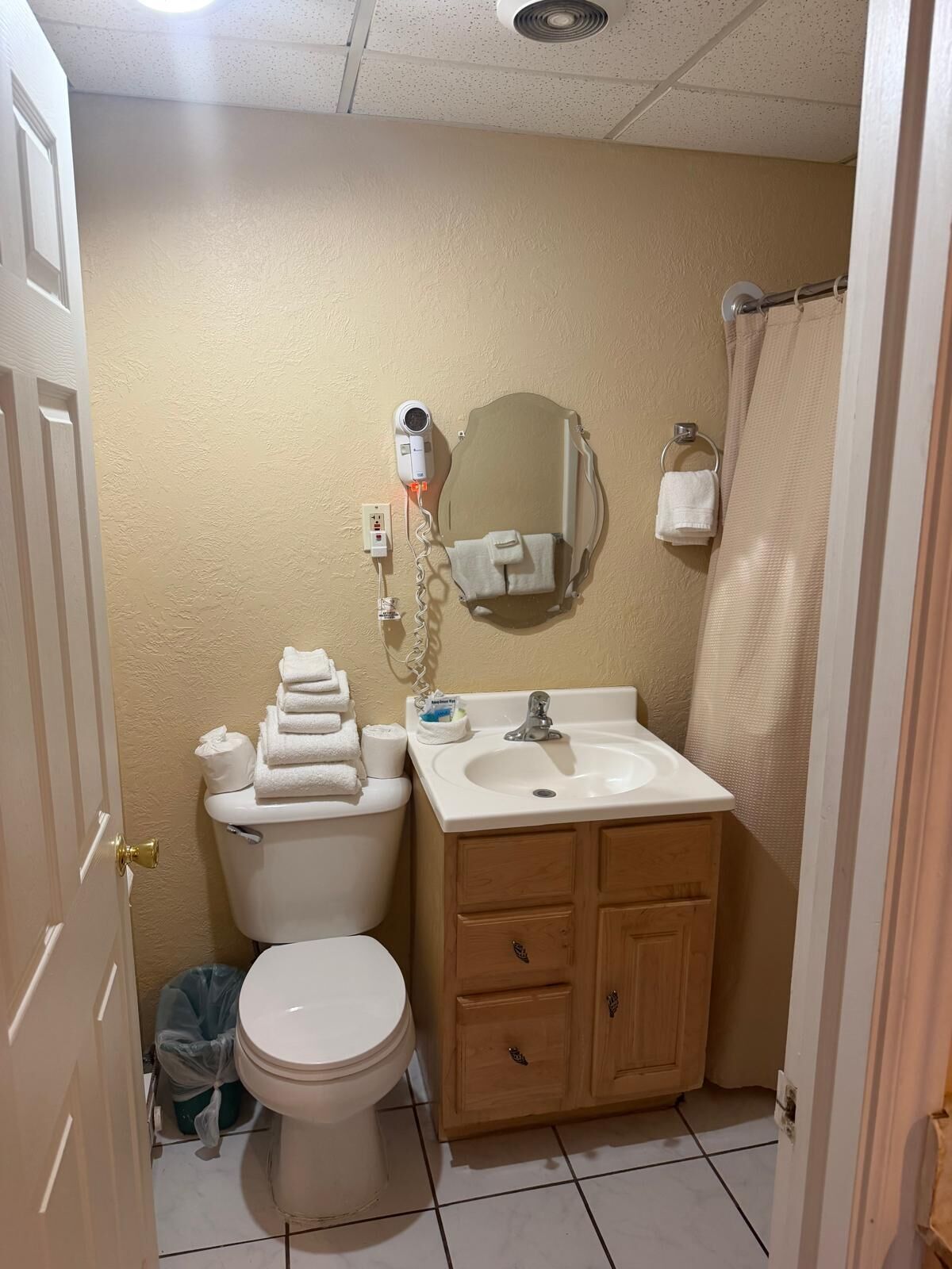 Un baño con inodoro, lavamanos, espejo y toallero.