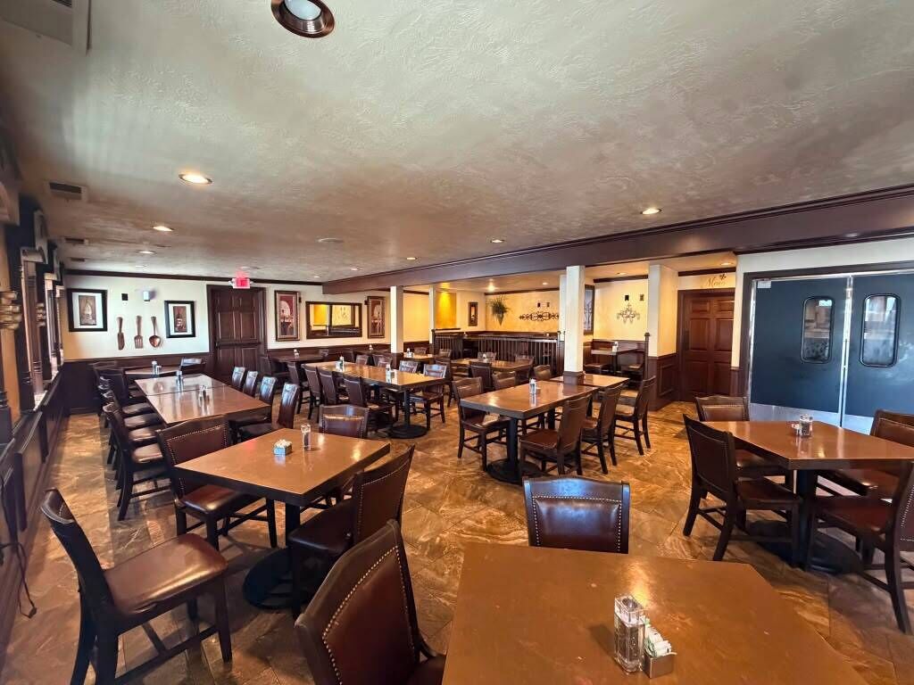 Un restaurante con múltiples mesas, cabinas y una zona de bar, además de una barra.
