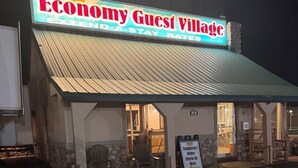 A building with a sign reading 'Economy Guest Village' and a temporary office sign.