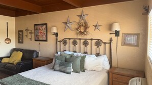Ein Schlafzimmer mit einem Bett, zwei Nachttischen, einer Wandlampe, einem gerahmten Bild und dekorativen Sternen.