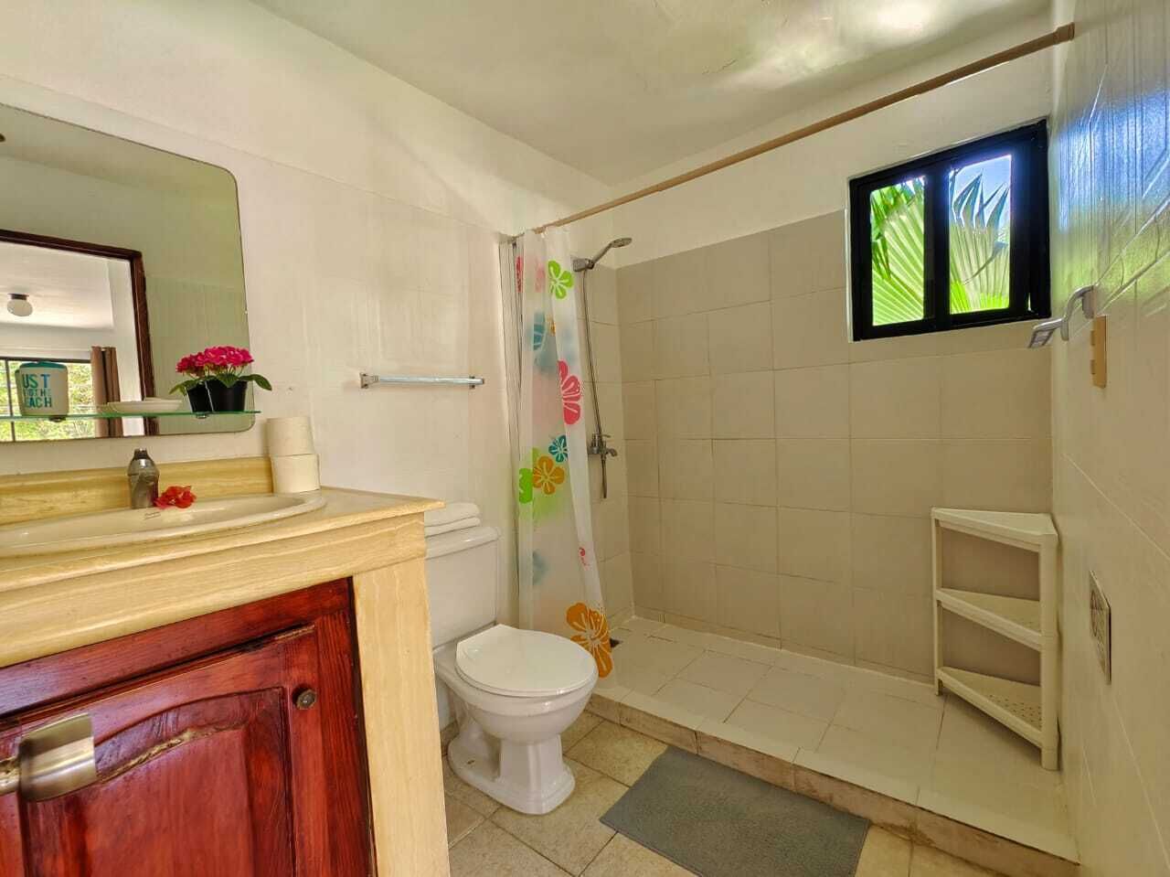 A bathroom with a toilet, shower, and sink.