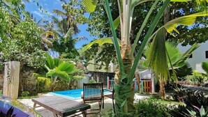A pool area with a wooden deck, a lounge chair, and a small table. - Riviera Punta Cana Eco Travelers House (Punta Cana)