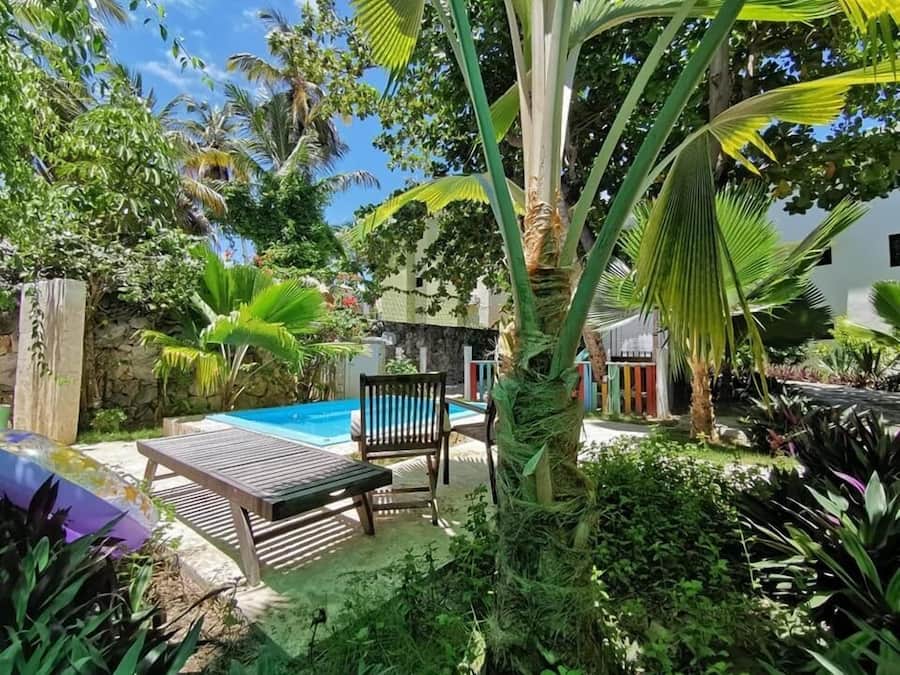 A pool area with a wooden deck, a lounge chair, and a small table.