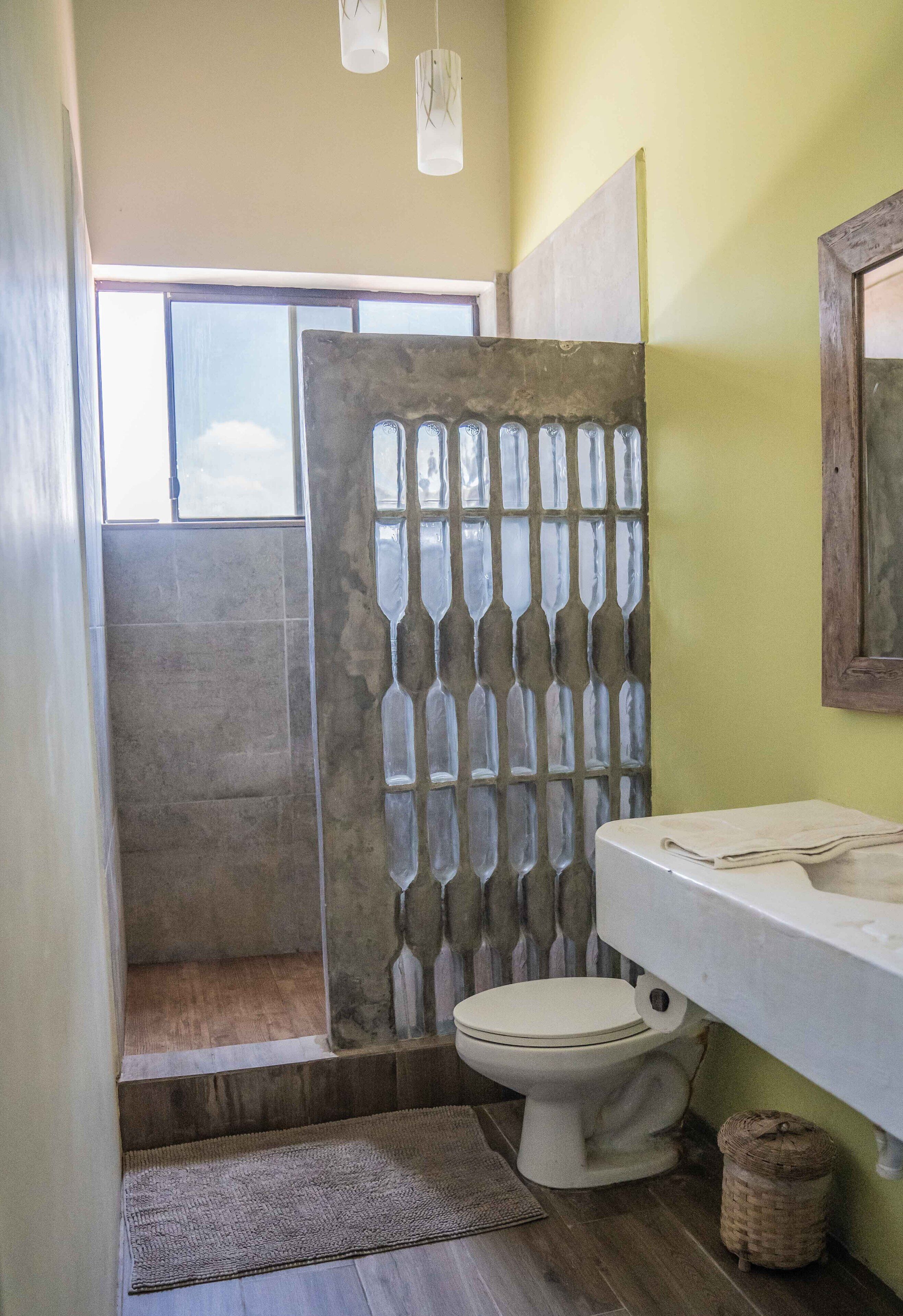 Une salle de bain comprenant des toilettes, un lavabo, un espace douche et une fenêtre.