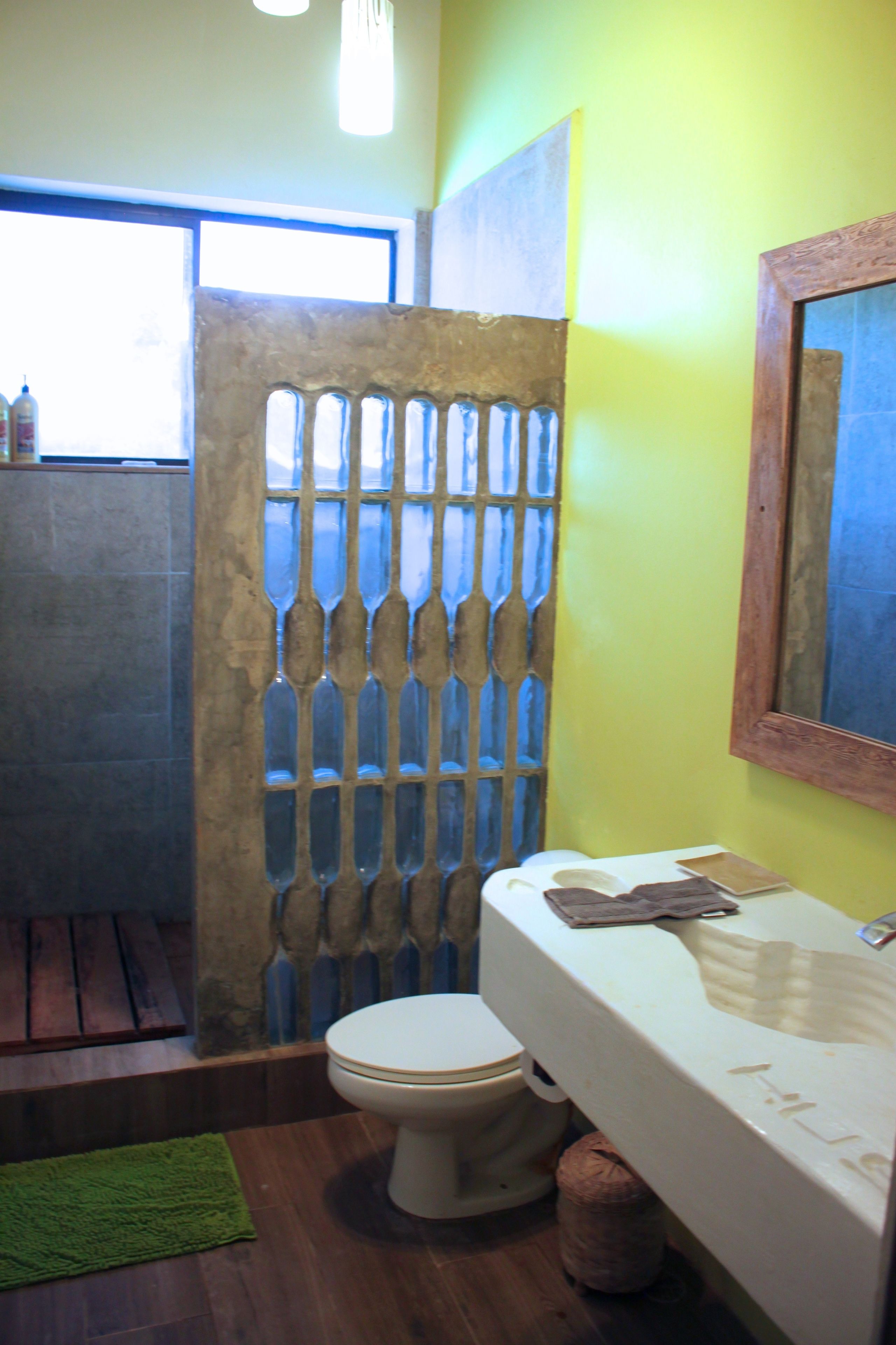 Une salle de bain avec un plancher en bois, des toilettes blanches, un lavabo blanc avec un miroir et un tapis vert.
