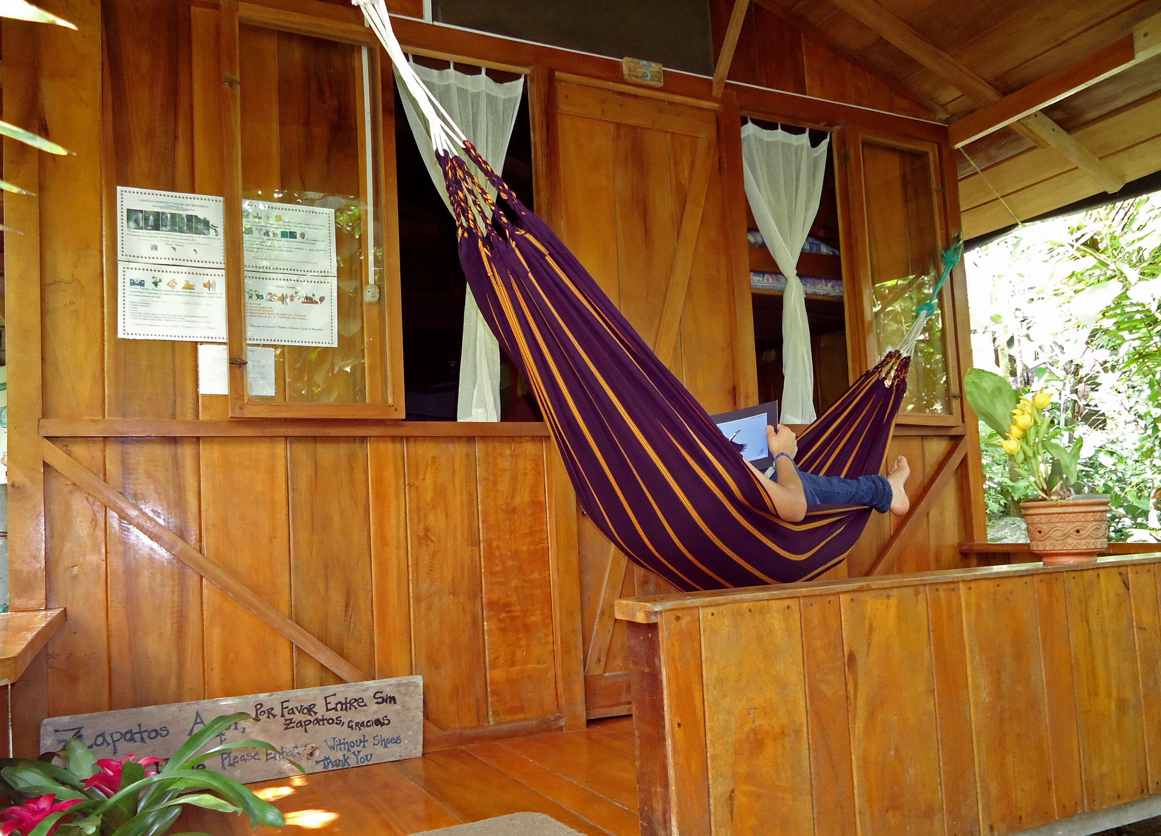 A wooden interior with a hammock, wooden walls, and a sign.
