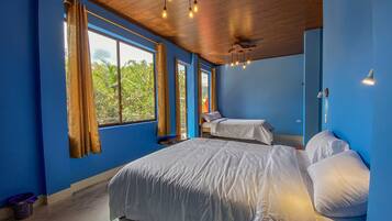 Una habitación con dos camas, ventanas amplias y techo con vigas a la vista y luces colgantes.