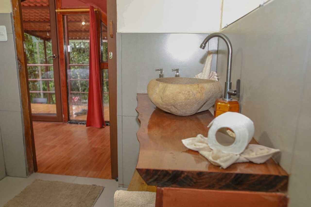 A bathroom with a stone sink, a towel, and a toilet paper roll.