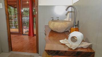 A bathroom with a stone sink, a towel, and a toilet paper roll.