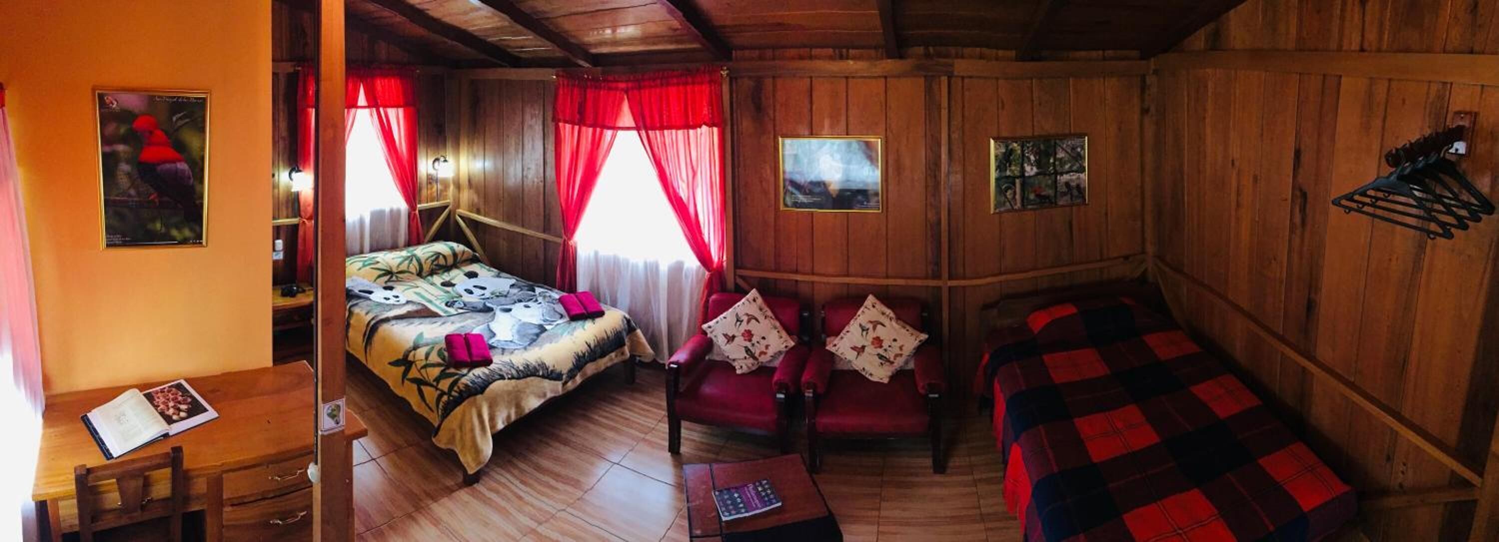 Ein Zimmer aus Holz mit einem Bett, einem Sessel, einem Tisch und einer Wandhalterung.