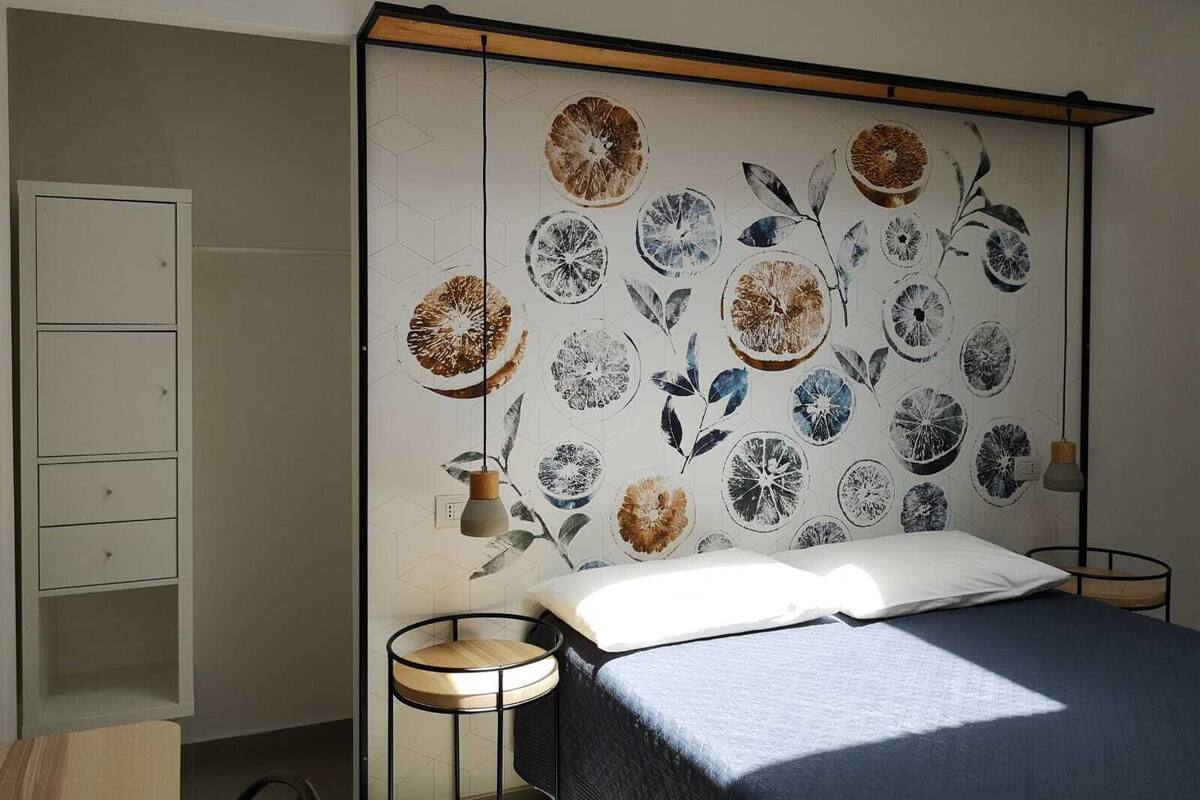 Un dormitorio con cama, mesitas de noche y una pared con diseño circular.