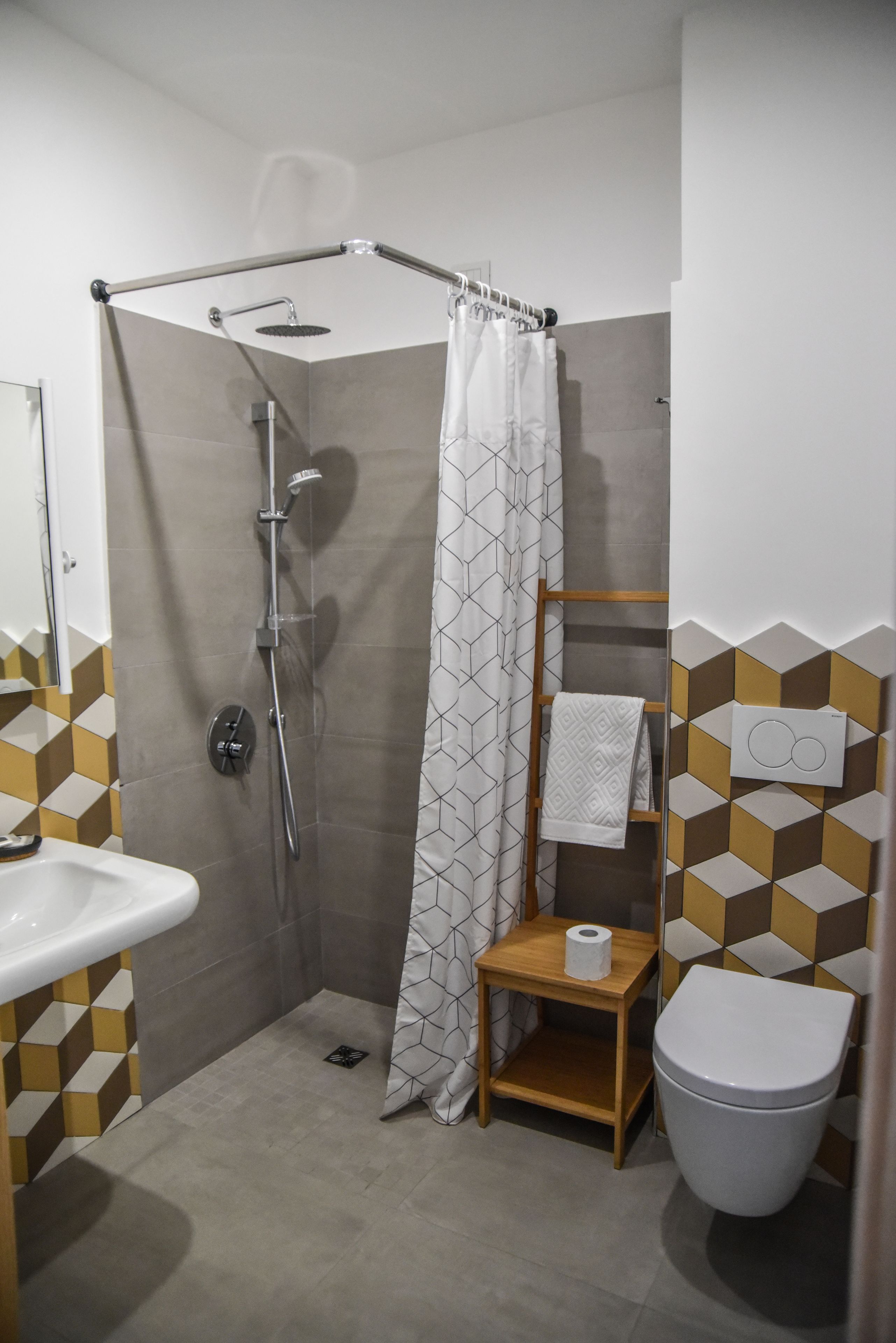 Baño con ducha, inodoro, lavamanos y toallero.