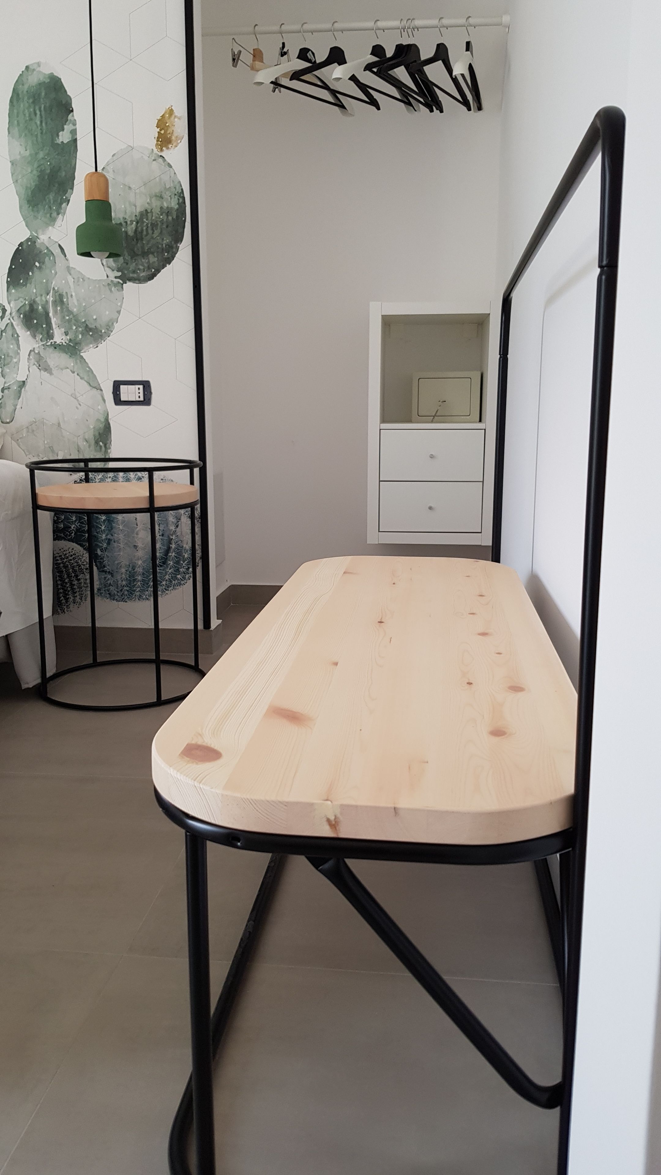 A minimalist room with a wooden table, a white cabinet, and a wall with geometric patterns.
