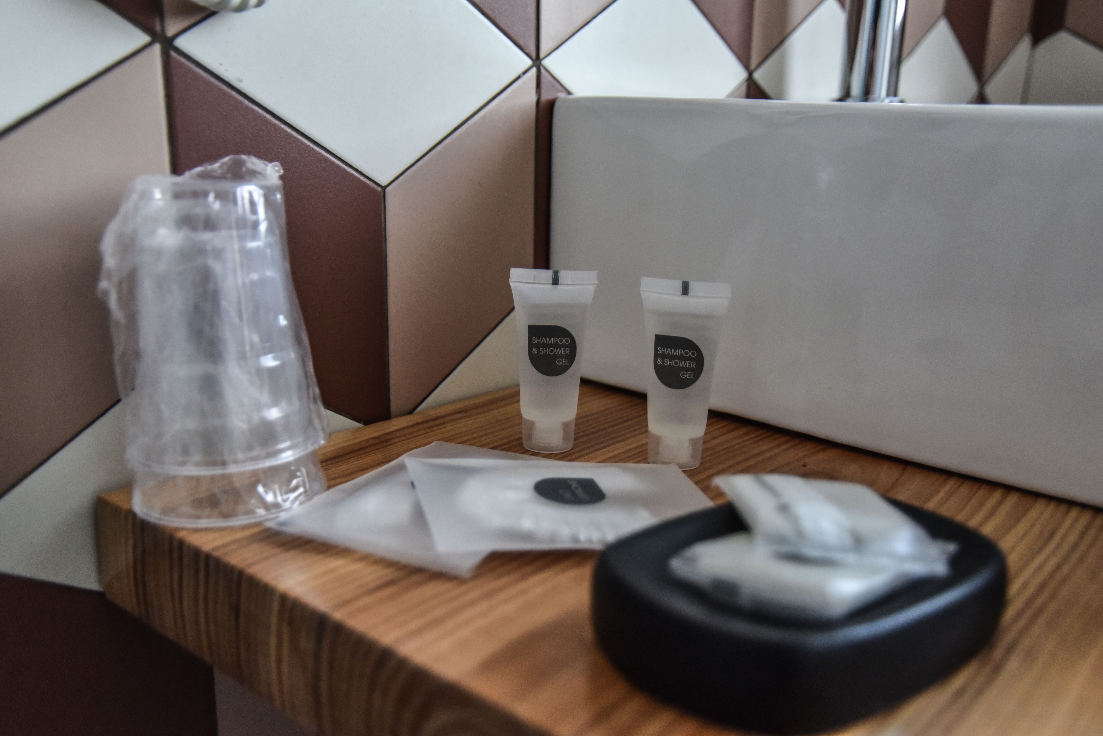 Ein Badezimmer-Waschtisch mit Pflegeprodukten, darunter eine Shampooflasche, Duschgeltuben und eine schwarze Haarbürste.