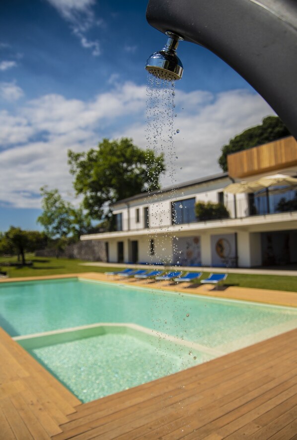 Piscina a l'aire lliure de temporada, para-sols i gandules