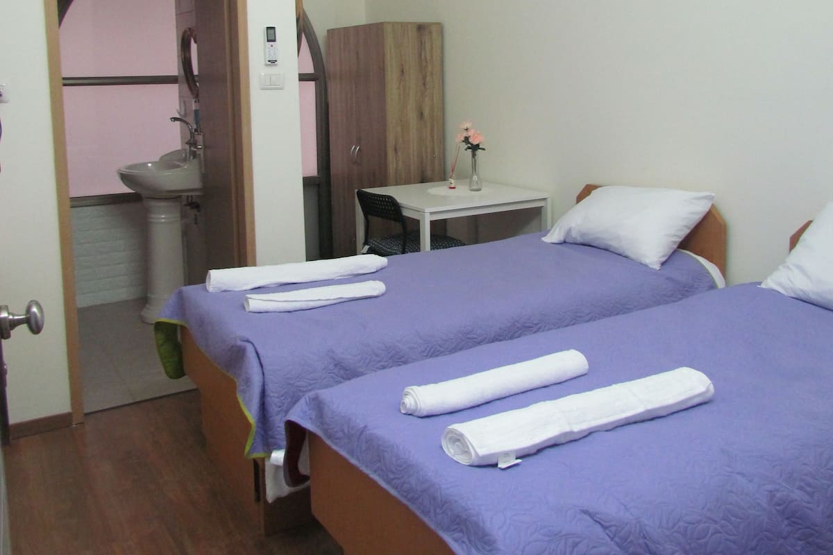 A hotel room with two beds, a bathroom, and a small desk.