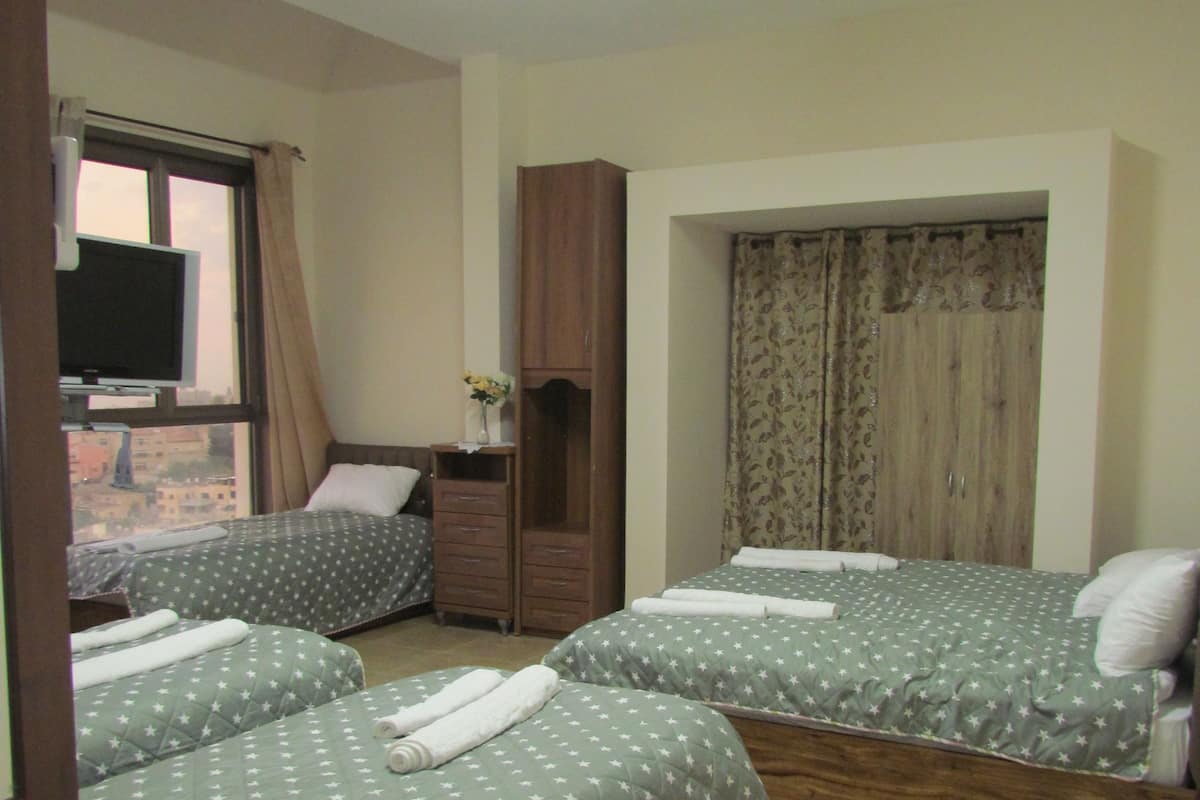 A hotel room with two beds, a wardrobe, a television, and a window with curtains.