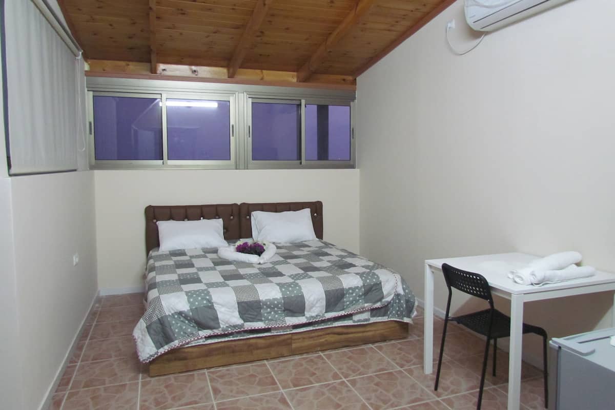 A bedroom with a bed, a desk, and a chair.