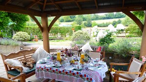 An outdoor dining area with a wooden table set for a meal, surrounded by wooden chairs. - Handywater Cottage B&B (Henley-on-Thames)