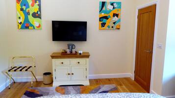 A bedroom with a bed, a TV, a cabinet, and two abstract paintings on the wall.