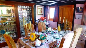 A dining area with a table set for breakfast, featuring a floral tablecloth, chairs, and various breakfast items. - Handywater Cottage B&B (Henley-on-Thames)