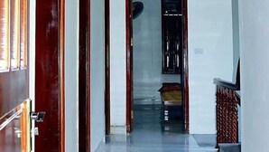Un pasillo con una puerta de madera a la izquierda, un cartel con el número 201 y una escalera a la derecha.
