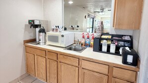 A kitchen with wooden cabinets, a microwave, a coffee machine, and a sink.