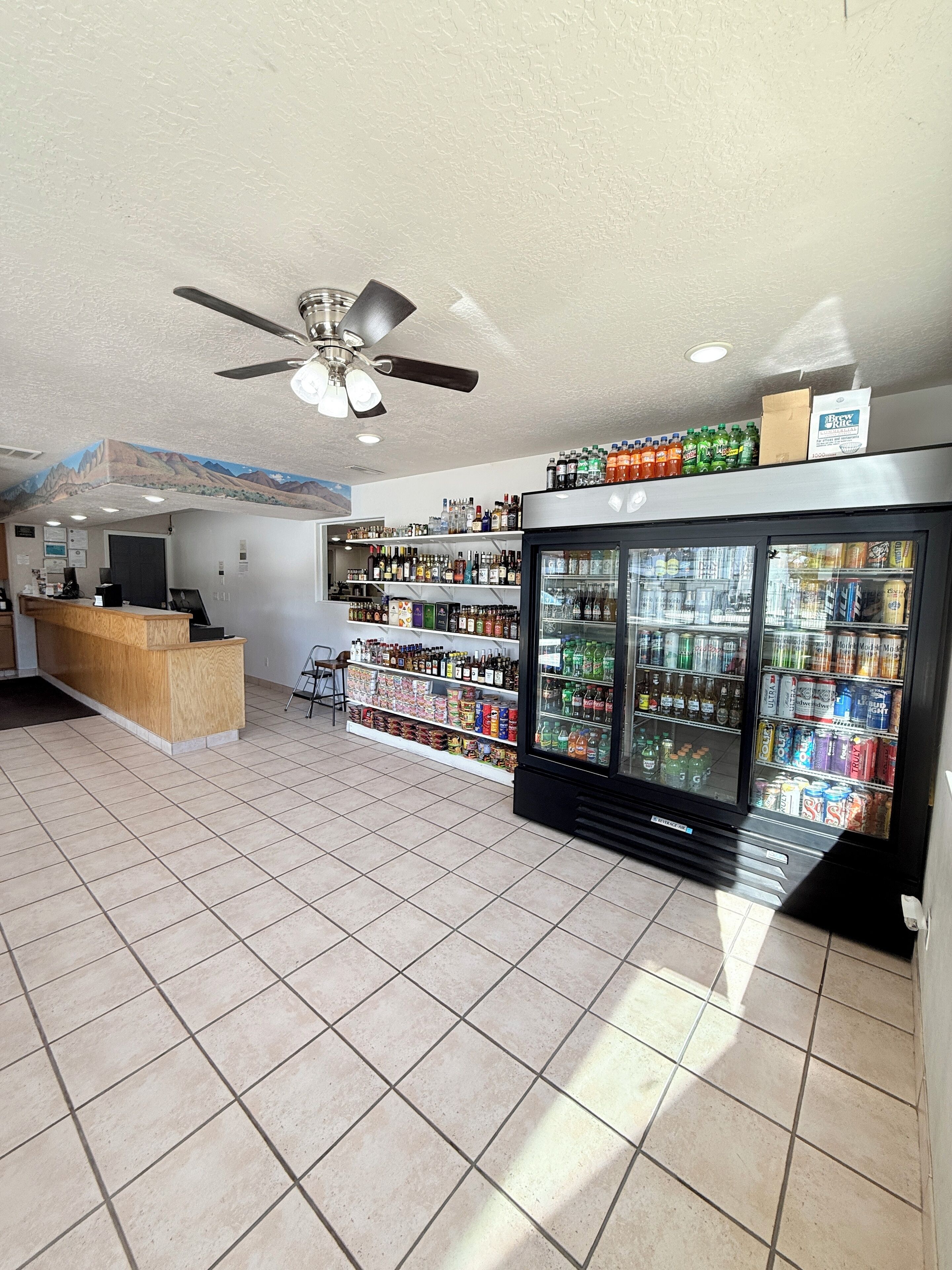 A spacious lobby with a reception desk, a ceiling fan, and a wall mural.