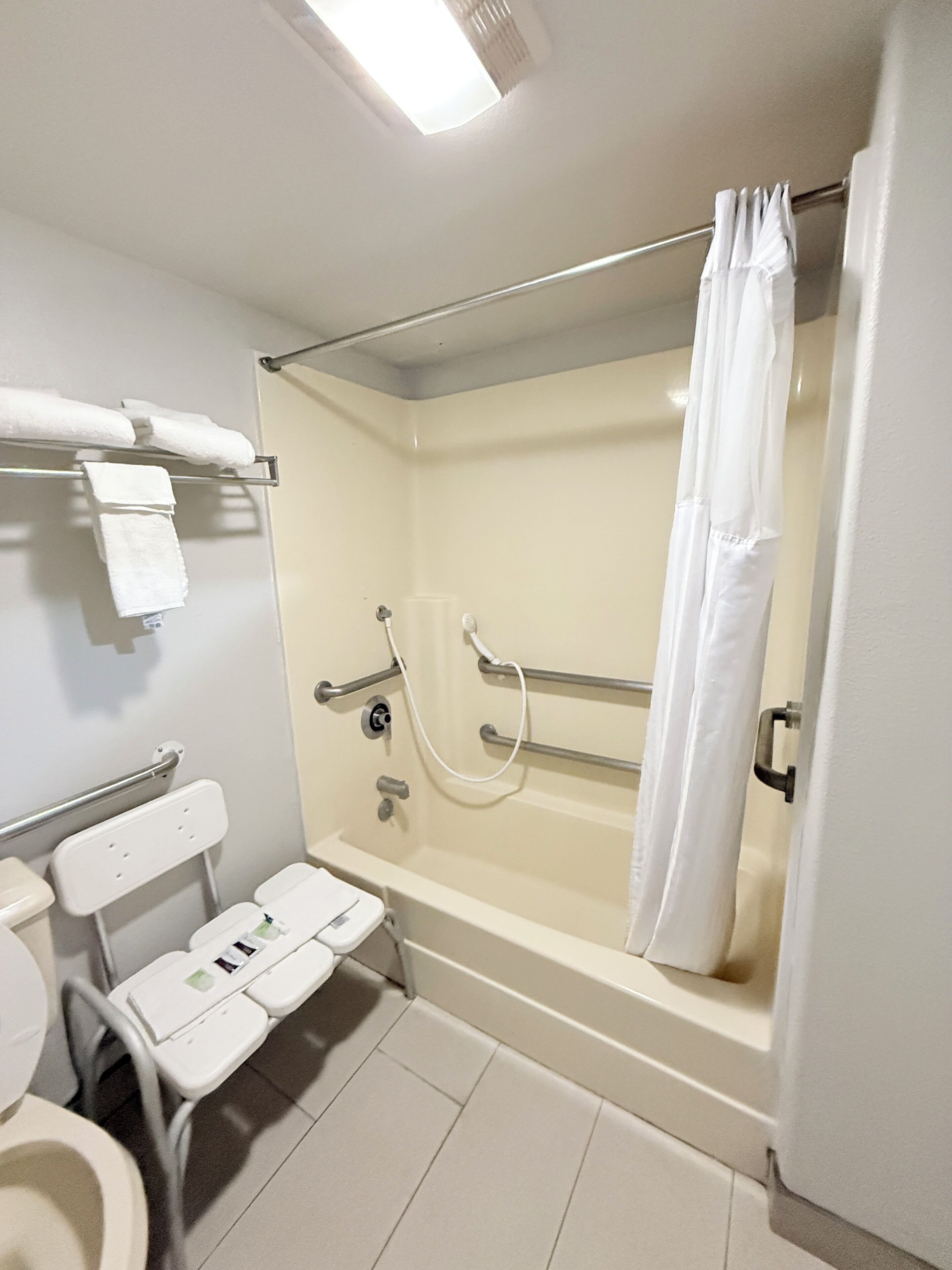 Un baño con bañera, inodoro y asiento de ducha.