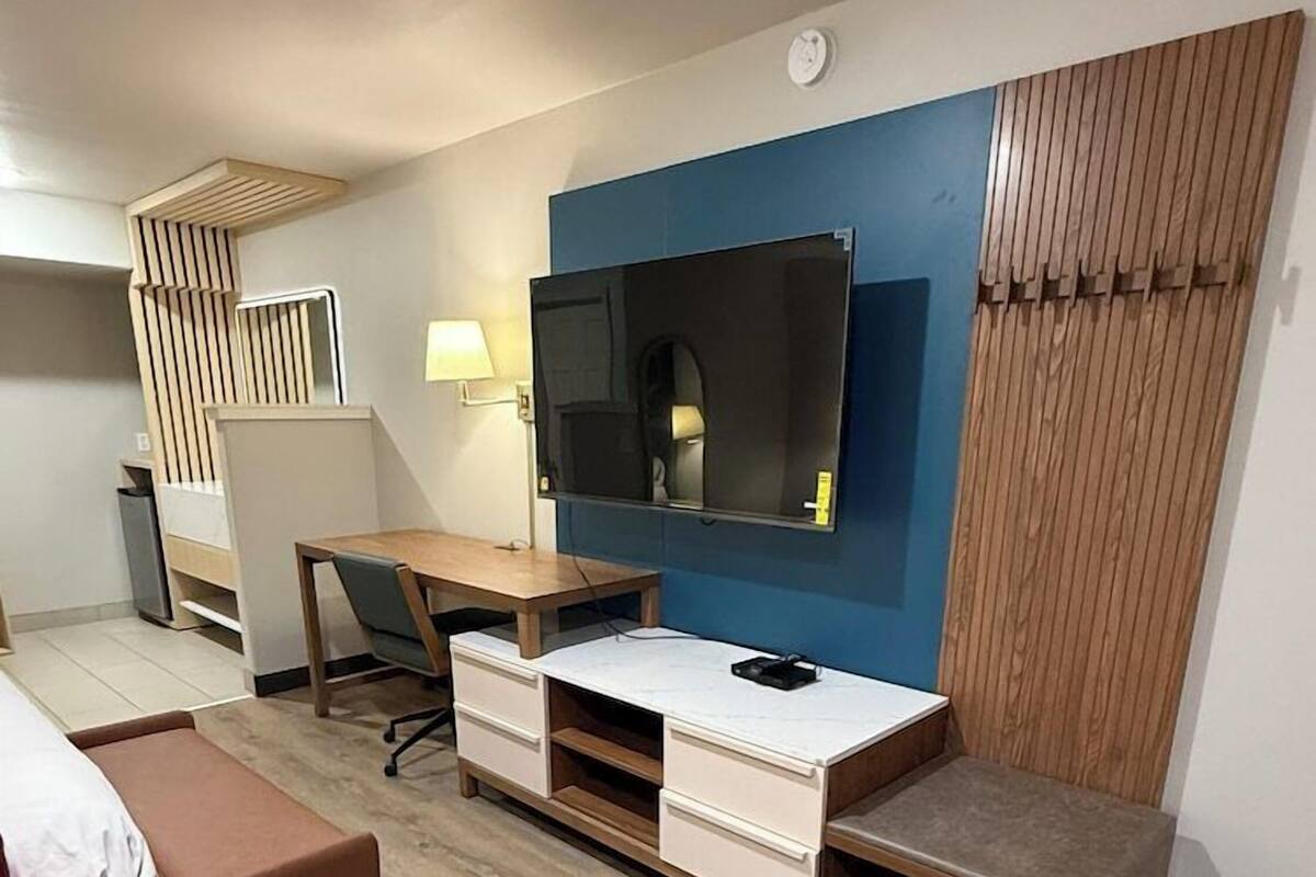 Une chambre d’hôtel équipée d’un lit, d’un bureau, d’une chaise, d’une télévision, d’une lampe et d’une poubelle.
