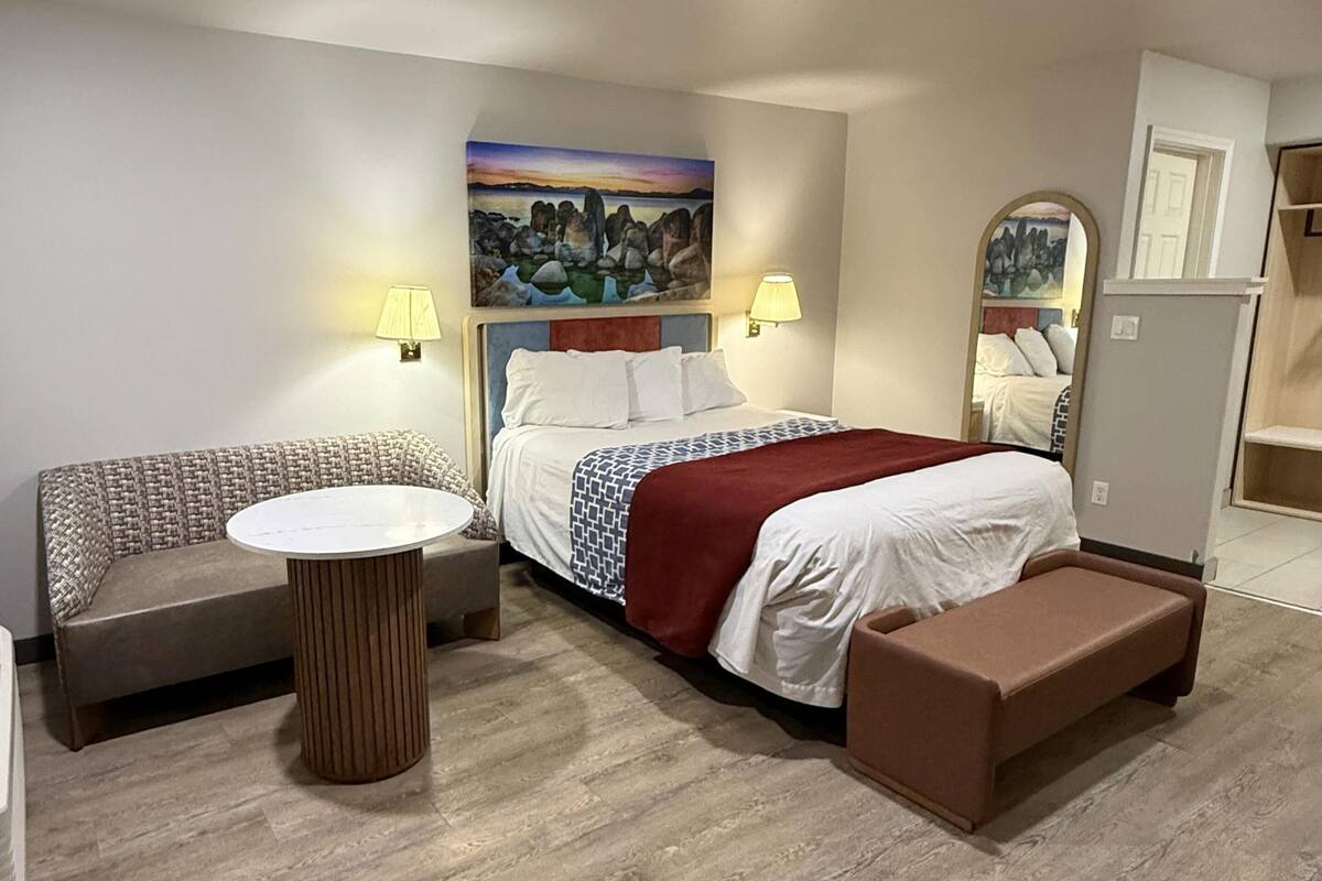 Une chambre d’hôtel avec un lit, un canapé, une table ronde et un banc.