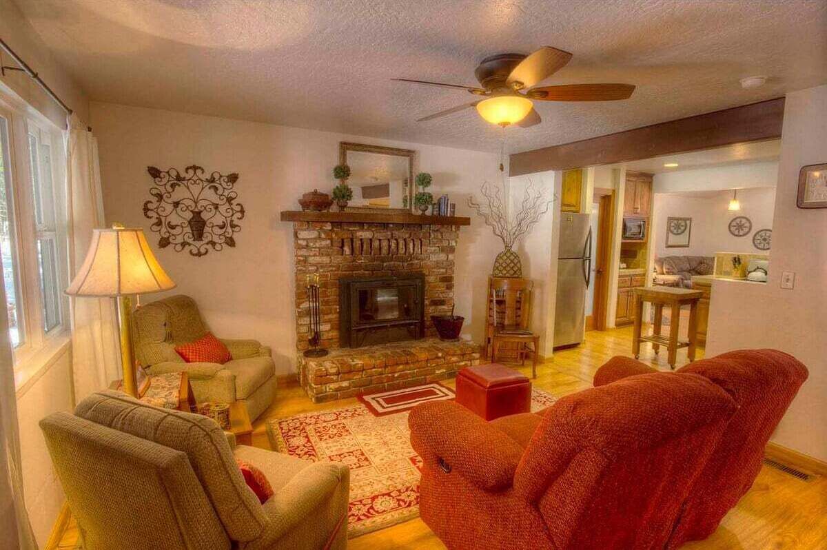 Een woonkamer met een open haard, een plafondventilator en een eethoek.