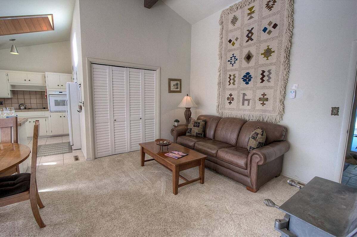 A living room with a brown leather sofa, a wooden coffee table, and a patterned rug.