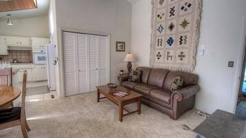 A living room with a brown leather sofa, a wooden coffee table, and a patterned rug.