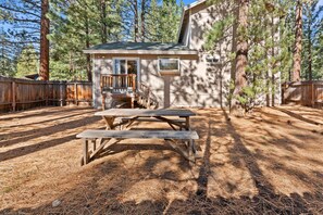 A cabin with a wooden deck, a picnic table, and a small porch.