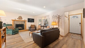 Una sala de estar con chimenea, un sofá, una mesa de centro y un televisor.