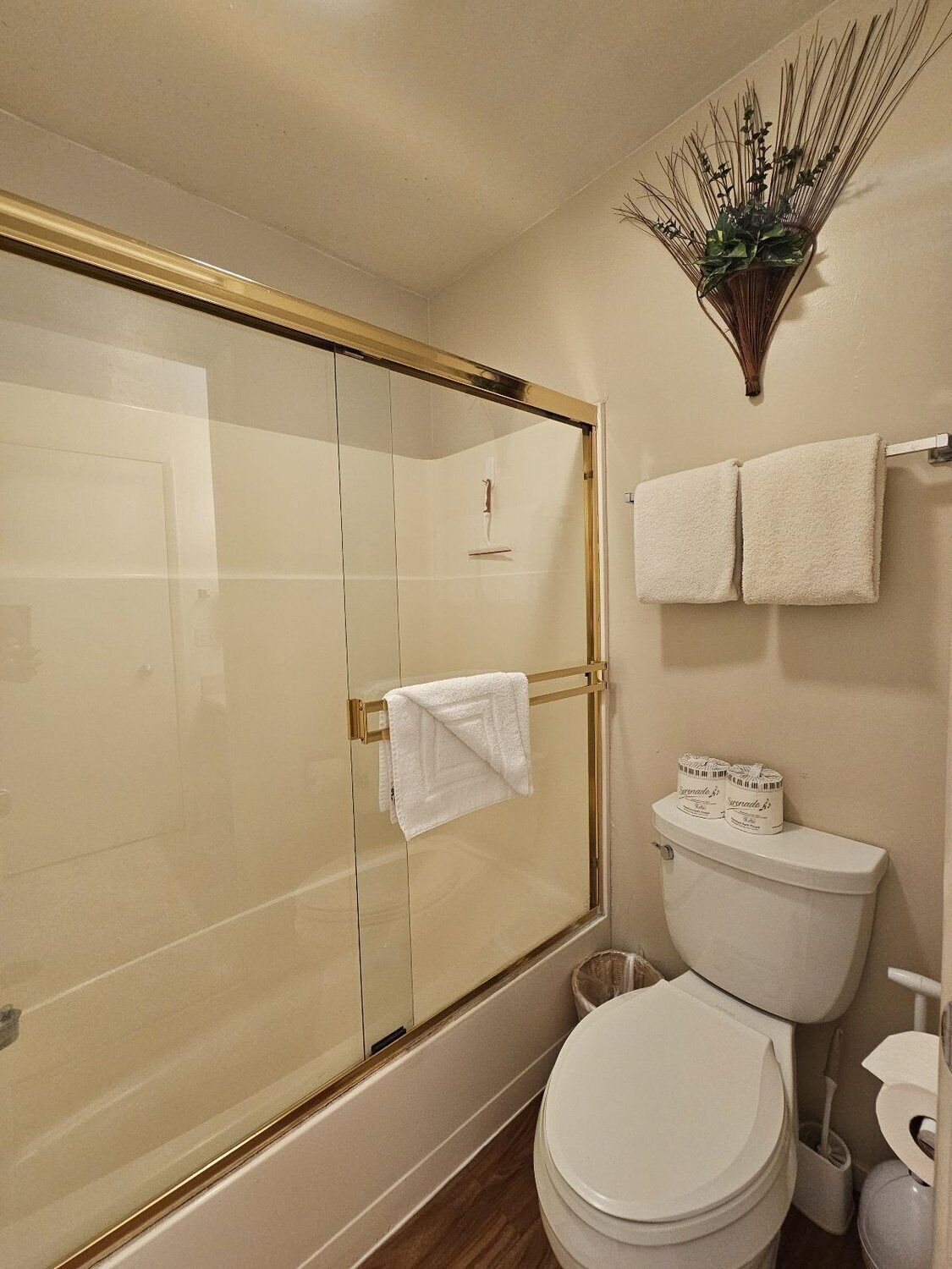 Ein Badezimmer mit einer gläsernen Duschkabine, einer Toilette und zwei Handtüchern auf einem Haken.