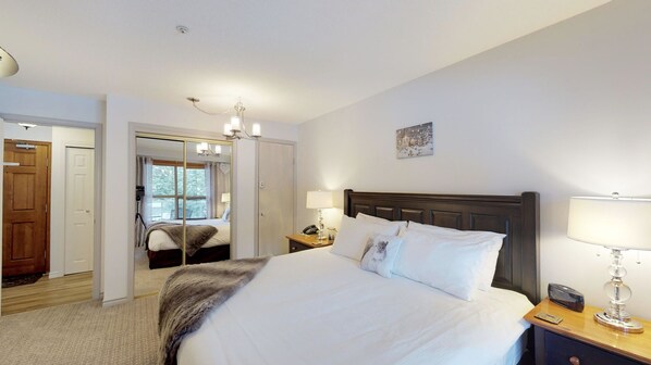 A hotel room with a large bed, bedside lamps, a wooden headboard, and a view of a balcony.