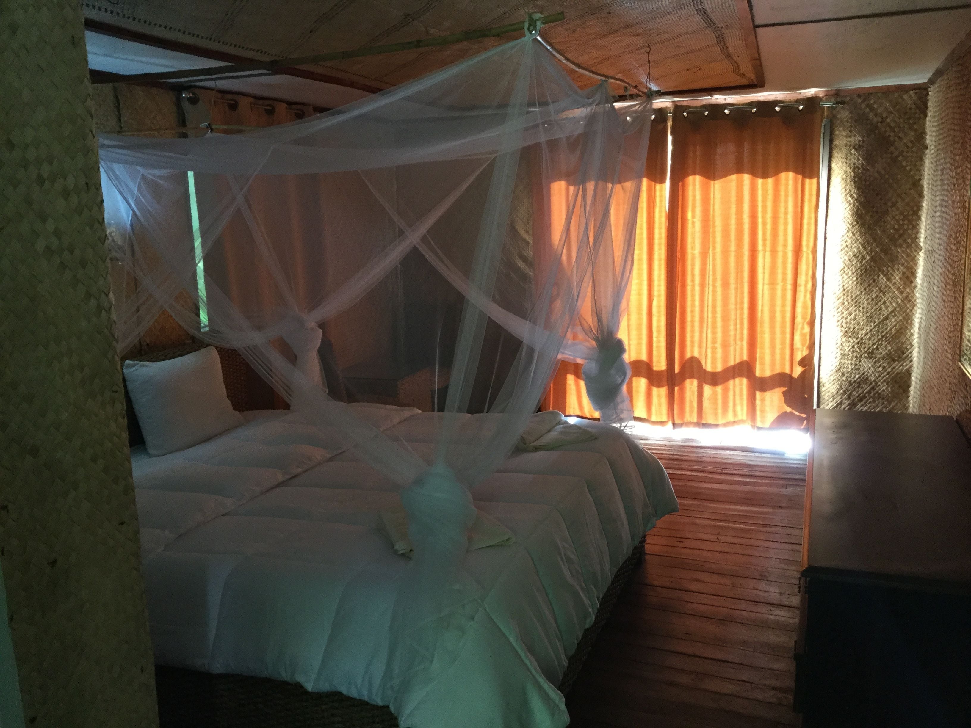 Ein Zimmer mit einem Bett, einem Nachttisch und einem fenster mit Vorhängen.