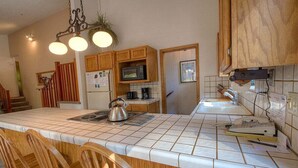 A kitchen with wooden cabinets, a microwave, a kettle, and a telephone. - Aspen View Lodge | BBQ | 2 Miles from Heavenly Ski (South Lake Tahoe)