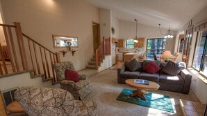 A cozy living room with a sofa, two armchairs, a coffee table, and a staircase leading to a kitchen. - Aspen View Lodge | BBQ | 2 Miles from Heavenly Ski (South Lake Tahoe)